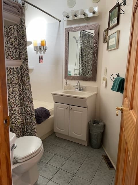 white bathtub with black/white shower curtain, white sink & base.