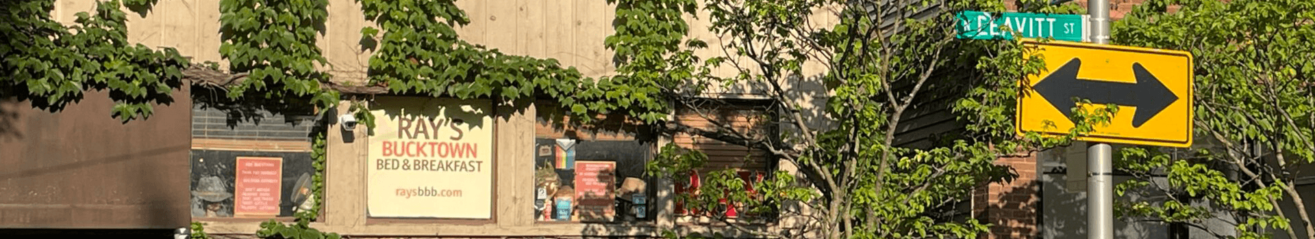 Sign for Ray's Bucktown Bed & Breakfast with a street sign indicating a left turn.