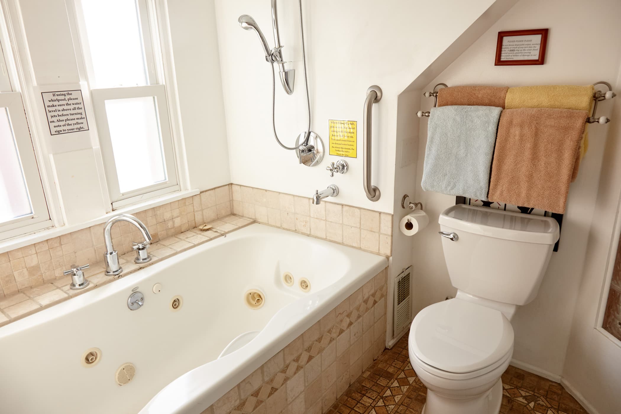 white whirlpool tub, white ceramic toilet and towel rack with towels. White curtains