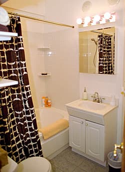 white bathtub with black/white shower curtain, white sink & base.