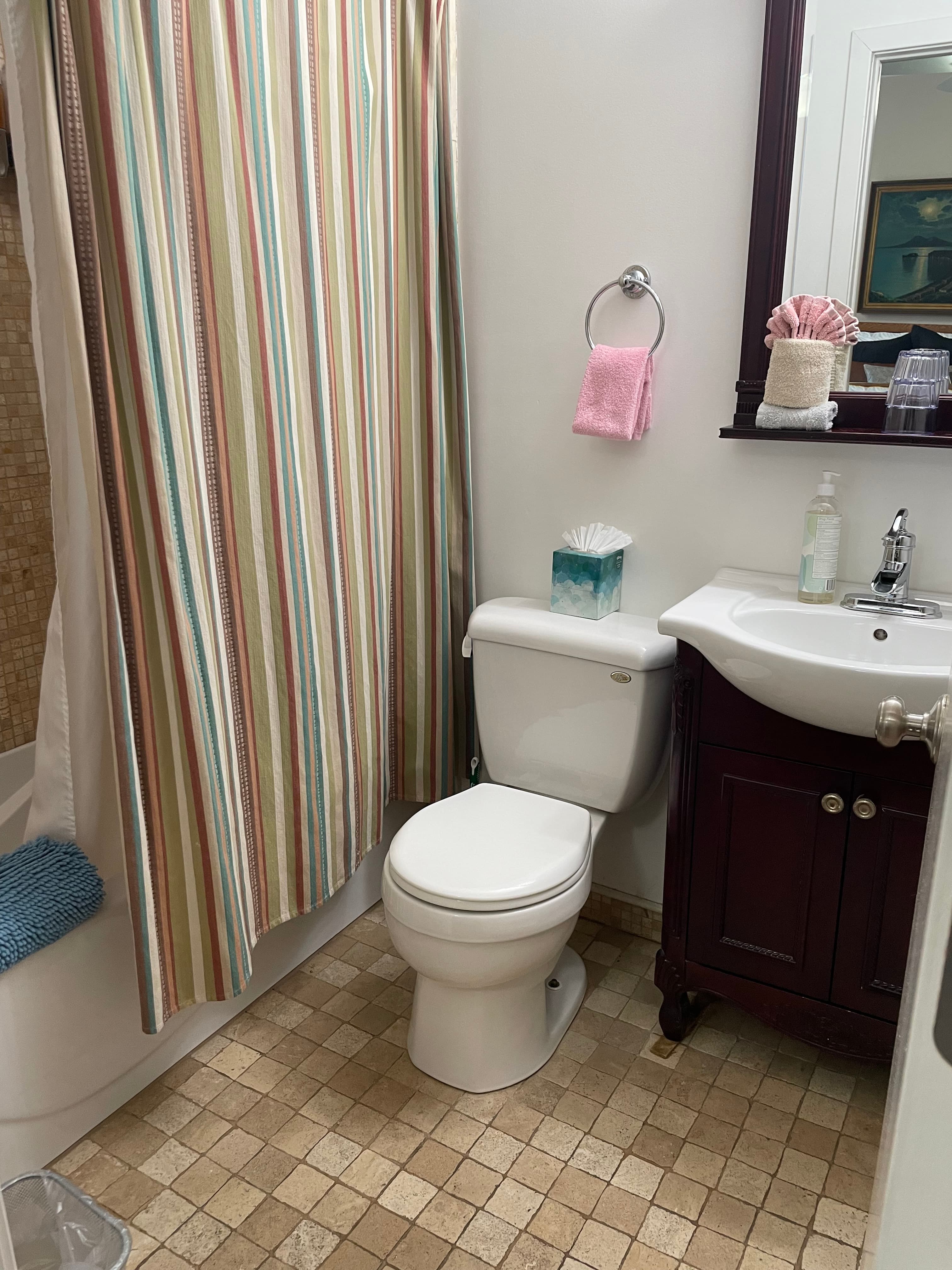 Bathroom with white sink, toilet, & tub and tumbled marble floor & shower stall tile.