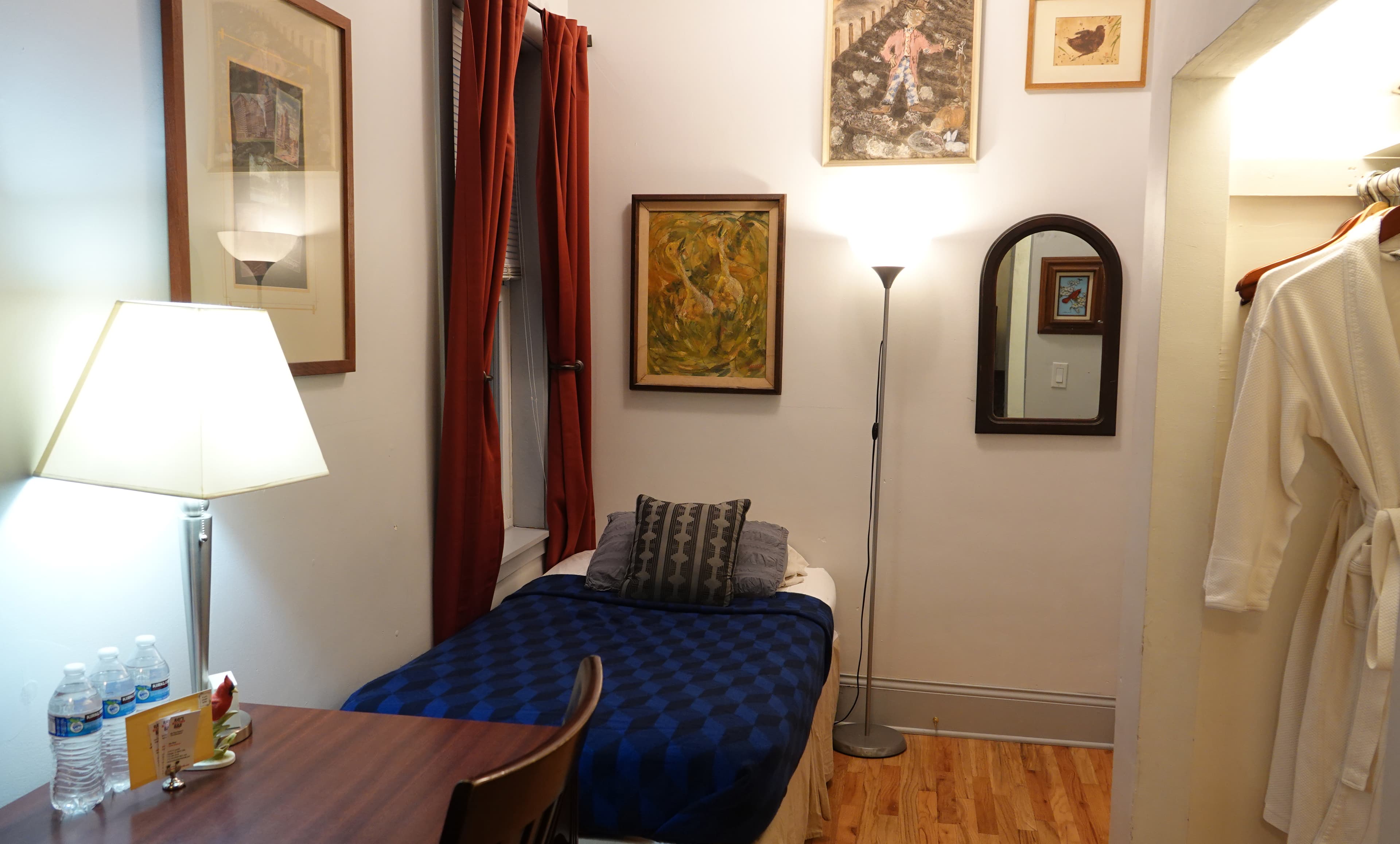 twin bed with sand color comforter, wooden desk and showing wood floors