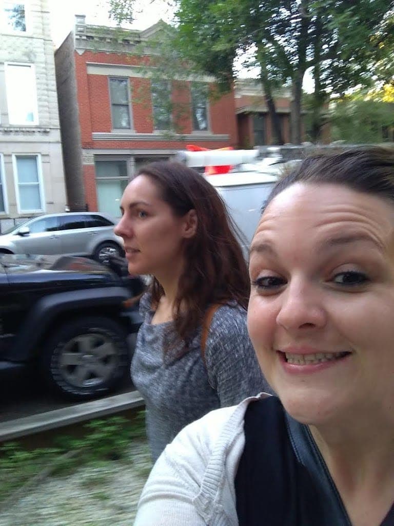 Smiling girl taking a selfie with girl passing in background Smiling girl taking a selfie with girl passing in background